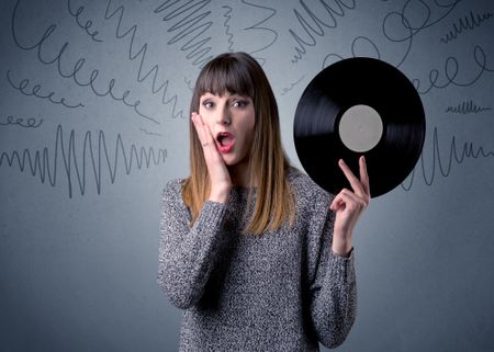 Young lady holding vinyl record on a grey background with scribbles around her