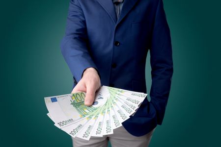 Young businessman holding large amount of bills