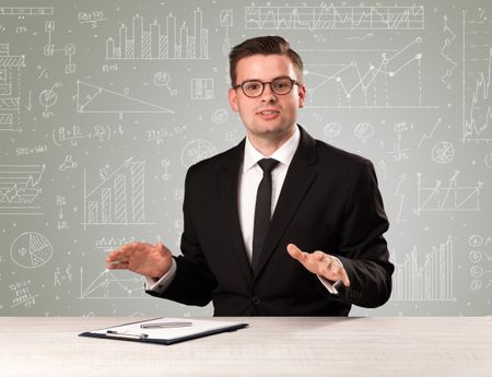 Young handsome businessman sitting at a desk with white graphs and calculations behind him