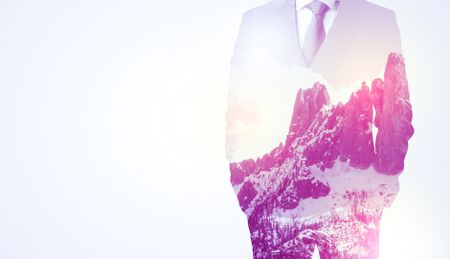 Young businessman in suit standing with sunny snowy mountain and trees graphic.