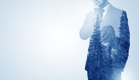 Young businessman standing and meditate with trees on the background 