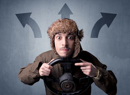 Young man holding black steering wheel with three arrows above his head pointing in different directions