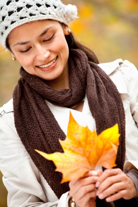 Autumn woman portrait holding a leaf and smiling