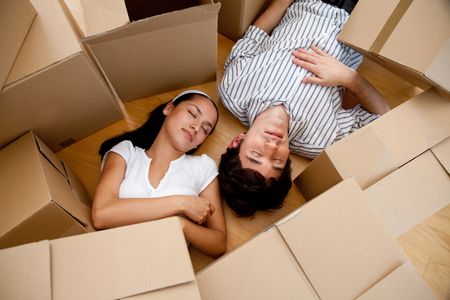 Couple tired of packing lying on the floor with boxes and sleeping