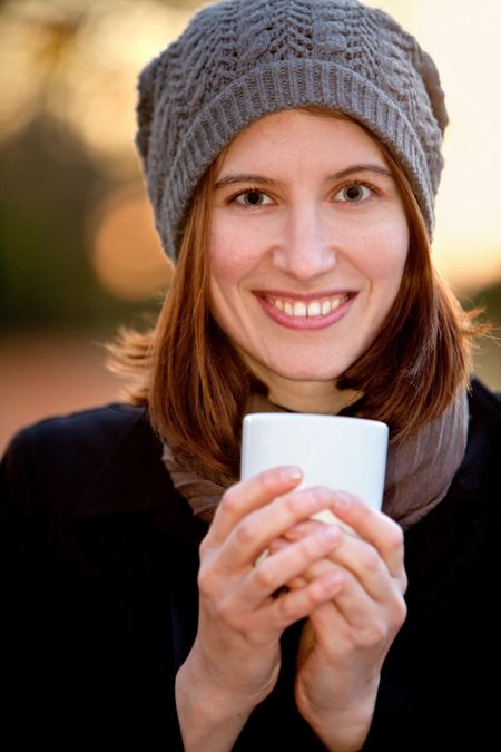 Winter woman drinking a cup of coffee ? outdoors