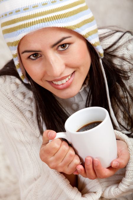 Winter woman drinking a cup of coffee - indoors