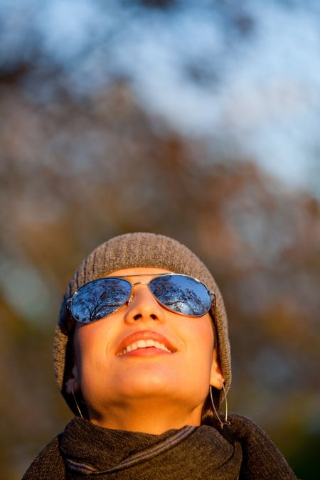Woman outdoors wearing sunglasses and looking at the sky