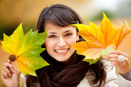 Portrait of an autumn woman holding leaves and smiling