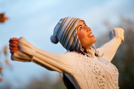 Woman at the park with arms open wearing warm clothes