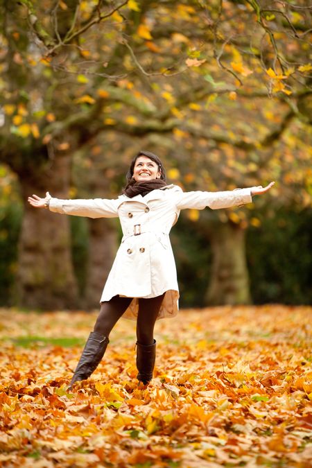 Happy autumn woman at the park with arms open
