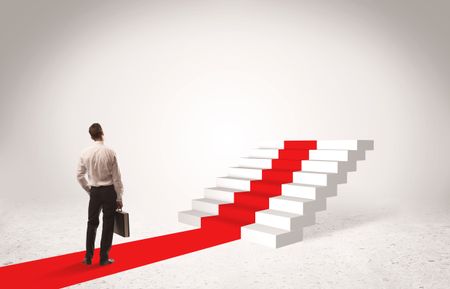 A successful businessman with briefcase standing on red carpet in front of steps in white space concept