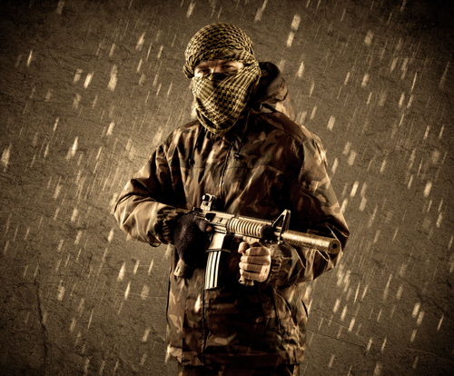 Portrait of dangerous heavily armed terrorist soldier with mask on grungy rainy background 