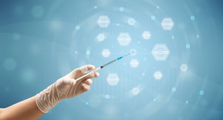 Female doctor hand holding syringe with blue background