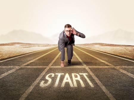 Young determined businessman kneeling before start line