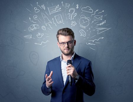 Businessman speaking into microphone with mixed doodles over his head