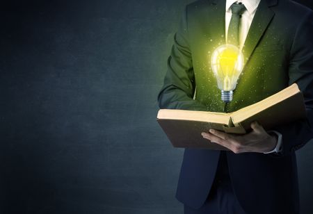 Businessman holding book with bulb.
