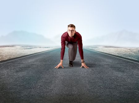 Young determined businessman kneeling before blank running track