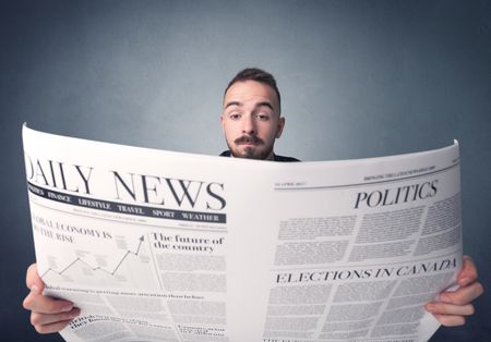 Young smart businessman reading daily newspaper