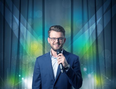 Businessman speaking into microphone with blue curtain behind him