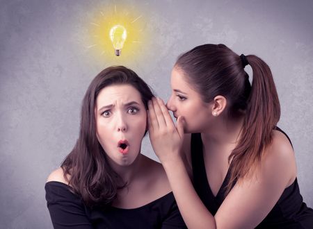 A young girl has an idea illustrated with a drawn glowing light bulb above the head, while a friend whispers a secret in her ear concept.