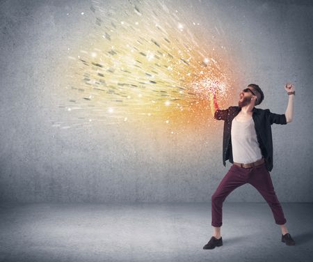 A young hipster guy with beard and sunglasses shouting in front of urban wall with vomit like colorful paint splatter on wall concept
