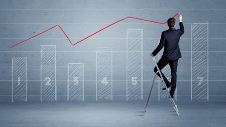 A man in elegant suit standing on a small ladder and drawing a chart on blue wall background with numbers, lines, blocks,