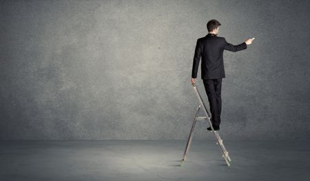 A man standing on ladder drawing with chalk in his hand on clear wall pattern background