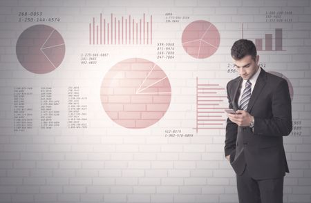 Young sales business male in elegant suit standing in front of brick wall background with lines and pie charts concept