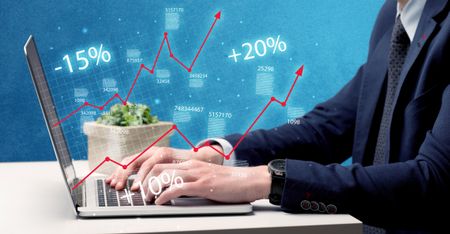 An elegant businessman working on graph statistics calculation using a laptop with clear blue background concept