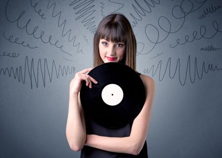 Young lady holding vinyl record on a grey background with scribbles around her