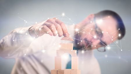 Young handsome businessman using wooden building blocks with interconnected lines and dots around him