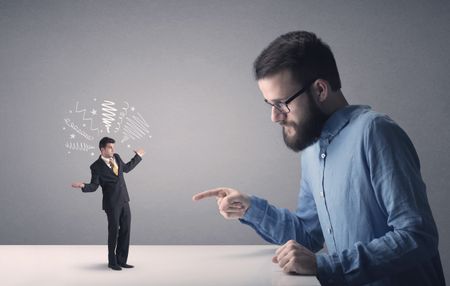 Young professional businessman being angry with an other miniature businessman who has scribbles above his head