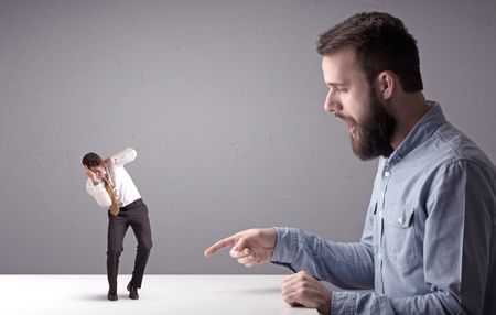 Young professional businessman being angry with an other miniature businessman in front of a splattered background