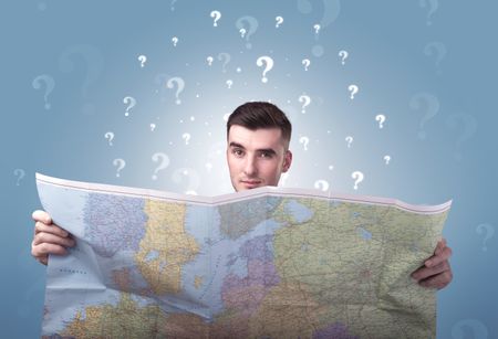 Handsome young man holding a map with white question marks above his head