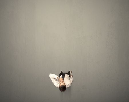 Young businessman contemplating a decision standing on a grey surface