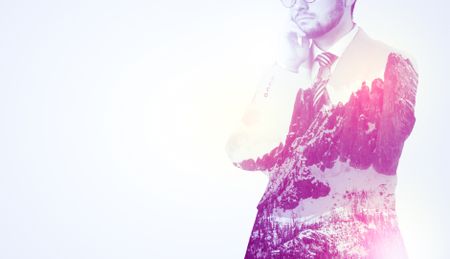  Young businessman in suit standing with sunny snowy mountain and trees graphic.