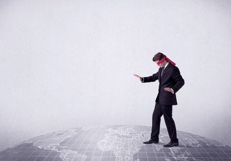 Young blindfolded businessman steps on a grey world map