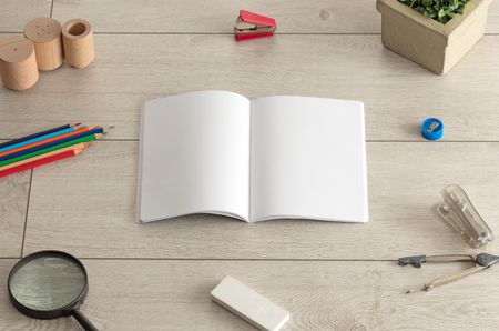 Empty notebook on wood floor with office tools nearby