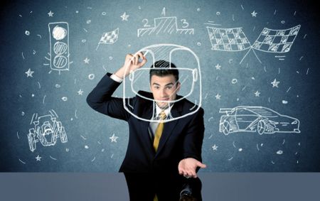 A happy businessman sitting at desk and drawing race car, flag, helmet around himself with a white chalk concept