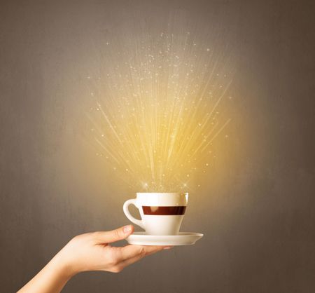 Young female hand holding coffee cup with a beam of light rising out of it 