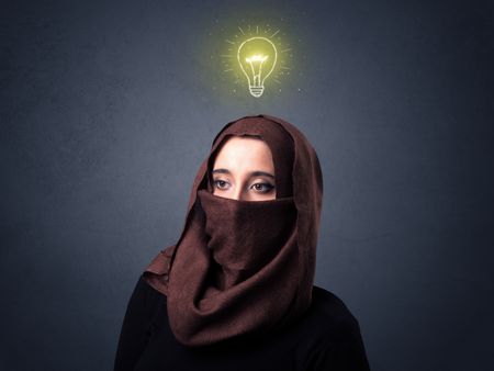 Young muslim woman wearing niqab with lit lightbulb above her head