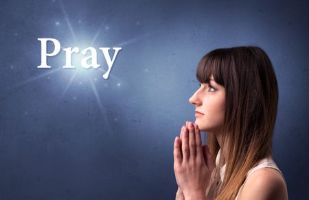 Young woman praying on a blue background with the word Pray written above her