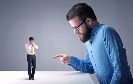 Young professional businessman being angry with an other miniature businessman 