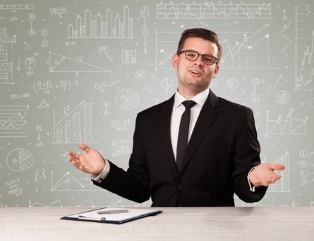 Young handsome businessman sitting at a desk with white graphs and calculations behind him 