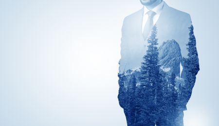 Young businessman standing and meditate with trees on the background 