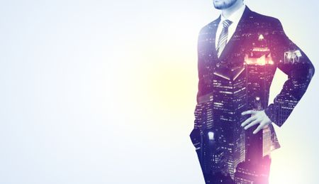 Young businessman thinking and standing with night skyscraper background