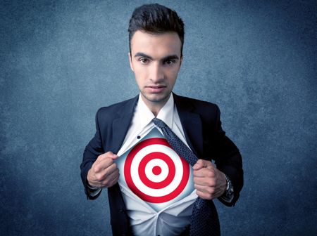 Businessman tearing his shirt off with target sign symbol on his chest concept on background