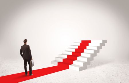 A successful businessman with briefcase standing on red carpet in front of steps in white space concept