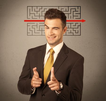 A young handsome business person making facial expression and solving maze with red arrow in front of clear, empty concrete wall background concept