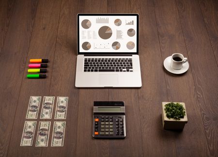 Pie chart graph icons and symbols on laptop screen with office accessories